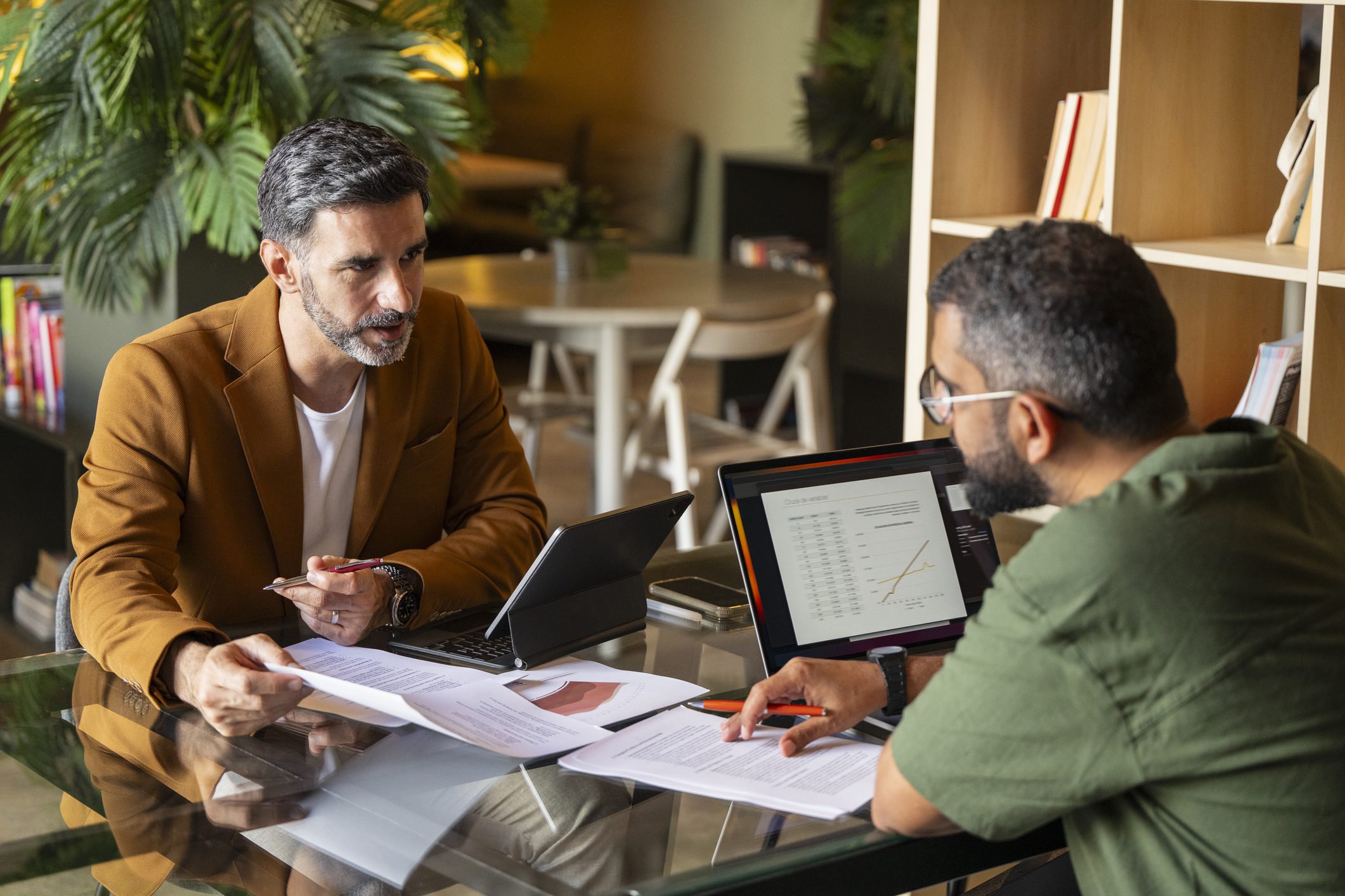 Two men discussing documents at table.