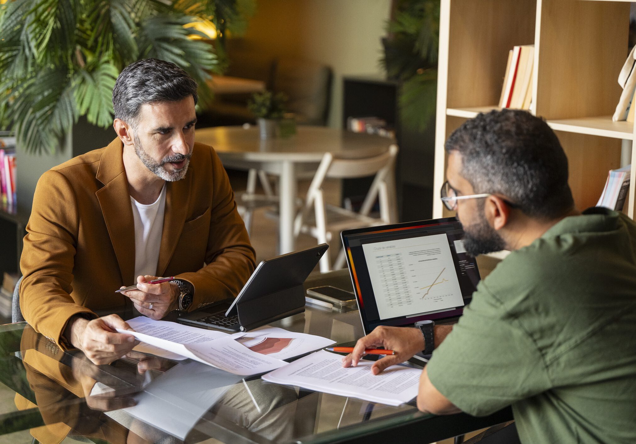 Two men discussing documents at table.